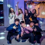 "Quinceañera posando con sus amigos para una foto, todos sonriendo y disfrutando del momento."