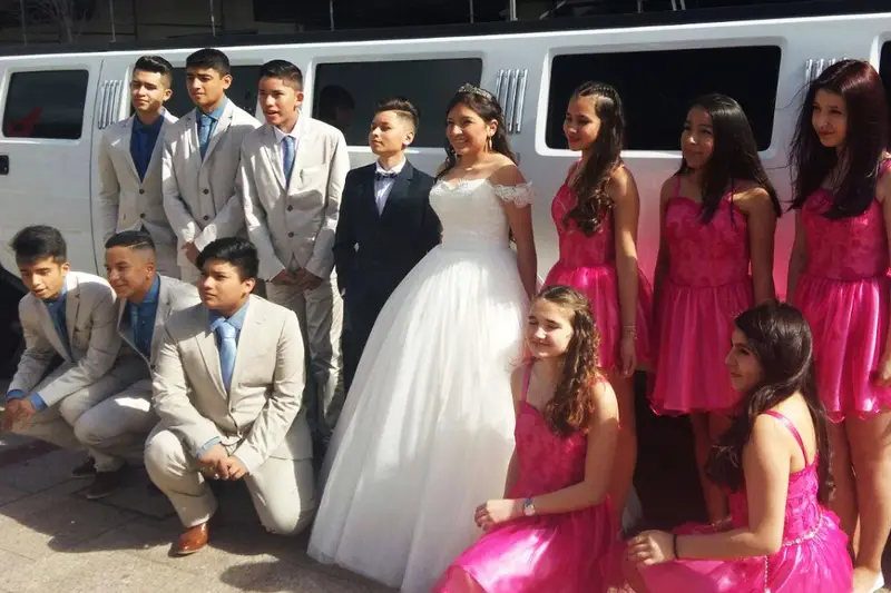 "Limusina Hummer con la quinceañera, su dama de honor y amigos posando para la foto antes de la celebración."